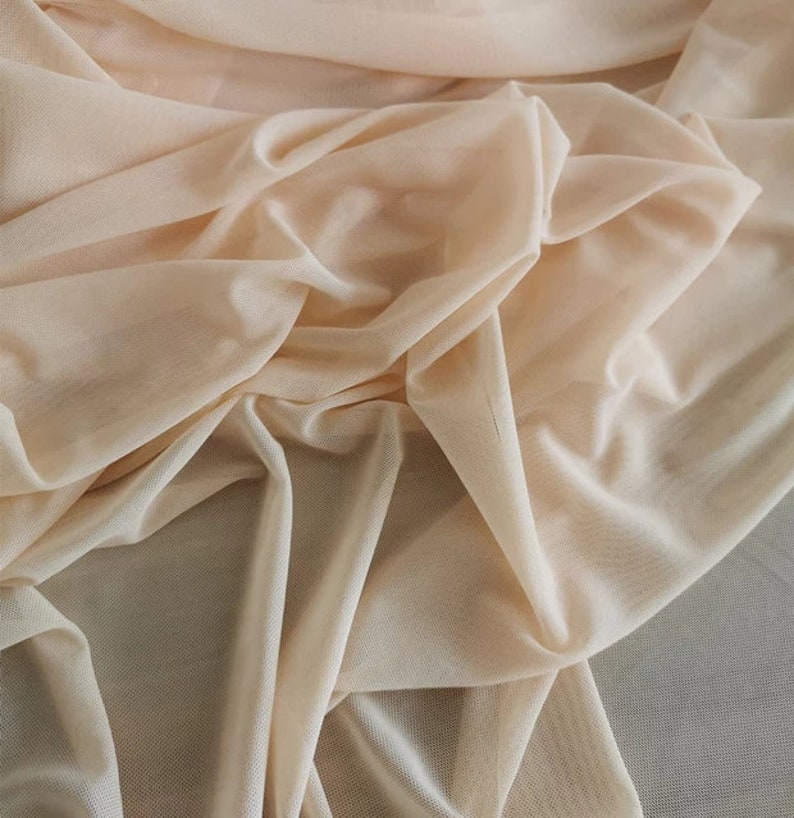 May include: A close-up of a sheer, peach-colored fabric. The fabric is soft and delicate, with a slightly textured surface.