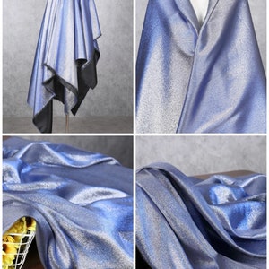 May include: A close-up of a silver fabric with a subtle shimmer. The fabric is draped over a mannequin and a table. The fabric is light blue in color.