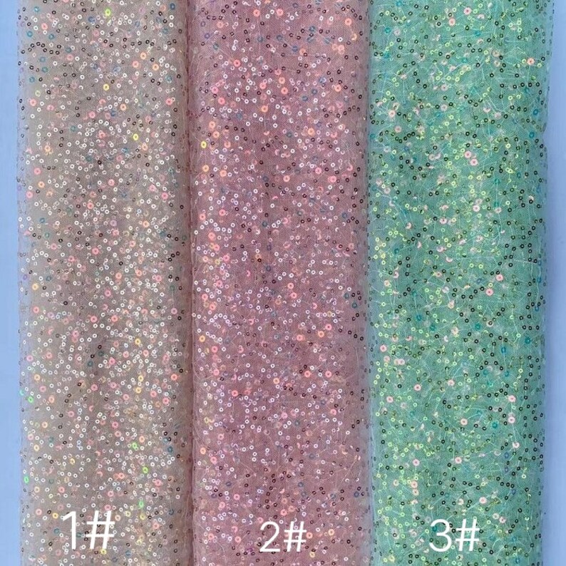 May include: Three swatches of iridescent sequin fabric in different colors: light silver, light pink, and light blue. The swatches are labeled 1#, 2#, and 3#.