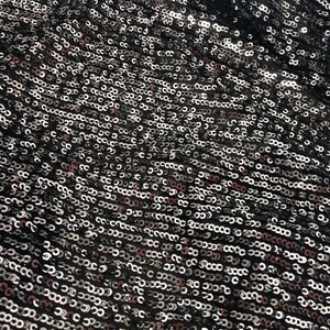 May include: Black fabric with silver and pink sequins. The sequins are arranged in a repeating pattern.