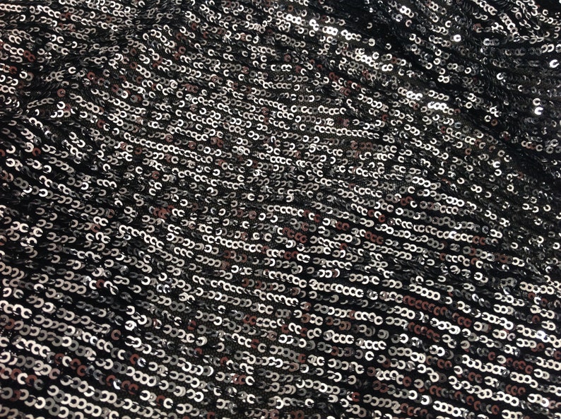 May include: Black fabric with silver and pink sequins. The sequins are arranged in a repeating pattern.