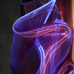 Peut inclure: Image abstraite d'un tissu fluide dans des tons violets et rouges. La matière semble transparente, la lumière se reflétant sur les plis, créant des reflets et des ombres. L'effet général est une sensation de mouvement et de fluidité.