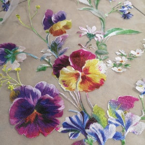 May include: Embroidered floral fabric featuring a range of colourful flowers, including purple, yellow, red, and blue. The fabric is sheer and delicate, and the flowers are intricately detailed.
