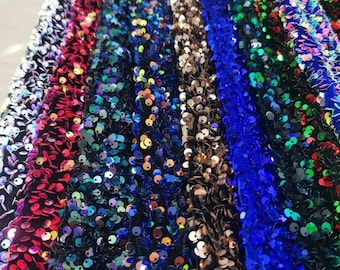 Puede incluir: Primer plano de una variedad de telas con lentejuelas de diferentes colores, incluyendo rojo, azul, verde y dorado.