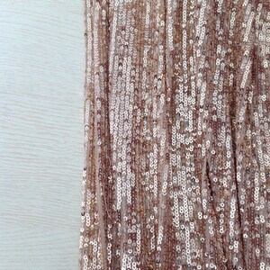May include: Close-up of a fabric with a shimmering gold and silver sequin pattern.