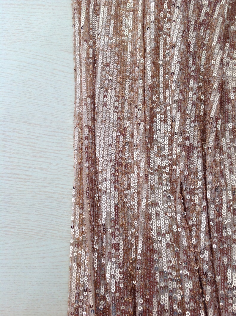 May include: Close-up of a fabric with a shimmering gold and silver sequin pattern.
