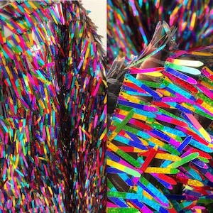 May include: Rainbow sequin fabric with long, thin sequins in a variety of colors. The sequins are sewn onto a black mesh backing.