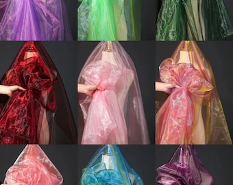 May include: Nine different colors of sheer iridescent fabric draped over a mannequin. The colors are purple, green, dark green, red, pink, peach, light pink, blue, and purple.