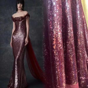 以下が含まれることがあります： 深みのあるボルドー色のロングのロングドレス。ドレスは体にフィットしたボディスと、流れるようなスカート。生地はキラキラと輝き、微妙な虹色の光沢があります。