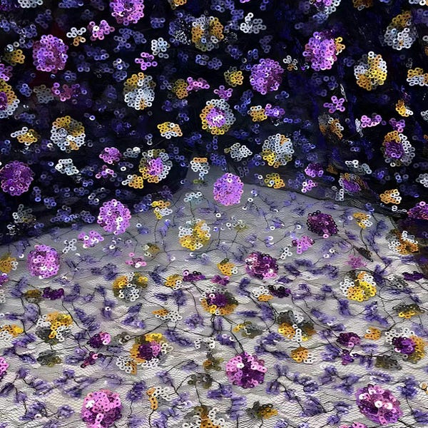 以下が含まれることがあります： 刺繍された花柄の複雑な模様が特徴の、透け感のある黒いメッシュ生地。紫、金、銀の鮮やかな色合いのきらめくスパンコールが密に装飾されており、密度が高く質感のある表面を作り出しています。