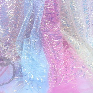 May include: A close-up of iridescent fabric with a delicate, patterned design. The fabric is layered in shades of light blue, pink, and white, creating a soft and ethereal look.