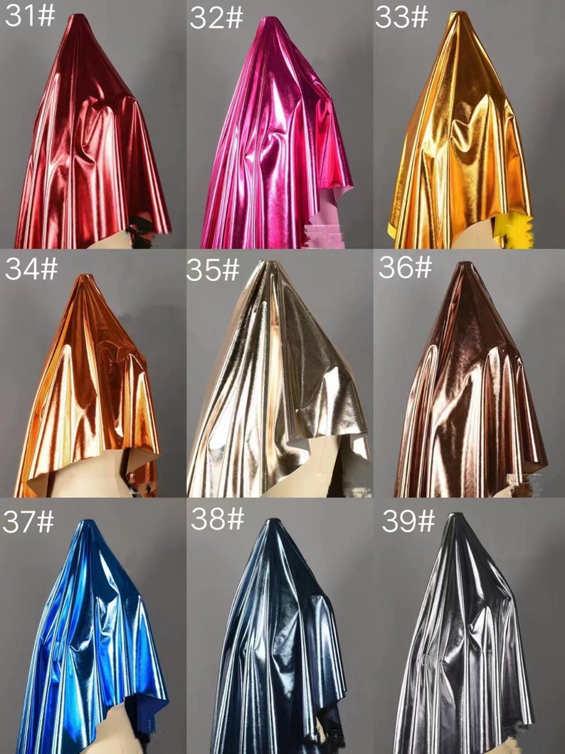 May include: Nine samples of metallic fabric in different colors, including red, pink, gold, orange, silver, bronze, blue, dark blue, and gray. Each sample is draped over a mannequin head.