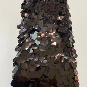 May include: Black sequined fabric with a mesh backing. The sequins are oval shaped and have a slight iridescent sheen.