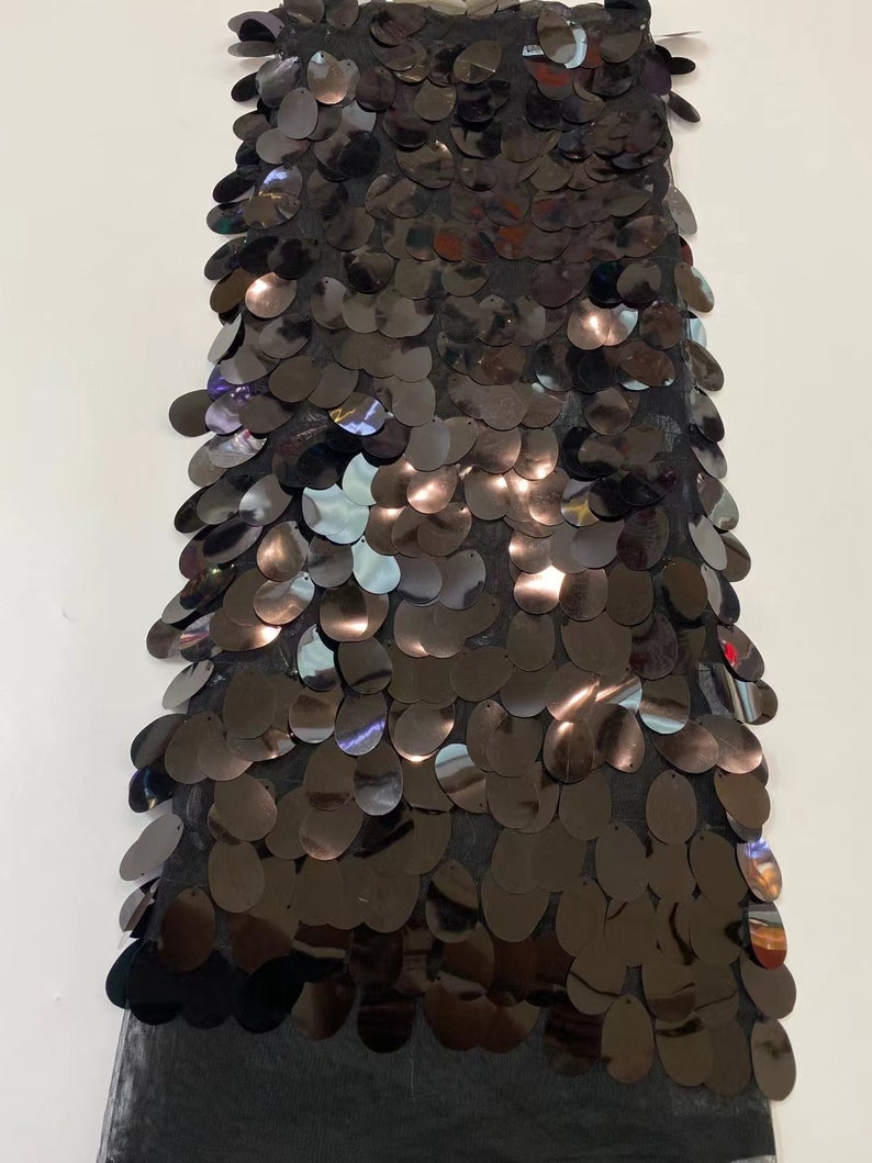May include: Black sequined fabric with a mesh backing. The sequins are oval shaped and have a slight iridescent sheen.