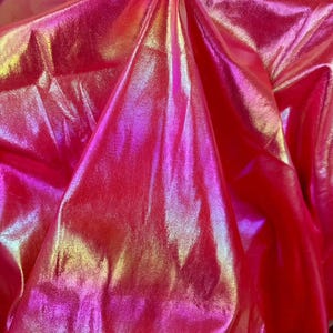 May include: Close-up of iridescent pink fabric with a subtle shimmer. The fabric is smooth and has a slight sheen.