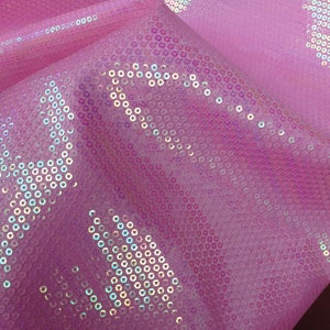 Op de afbeelding: Roze stof met iriserende pailletten in een geometrisch patroon.