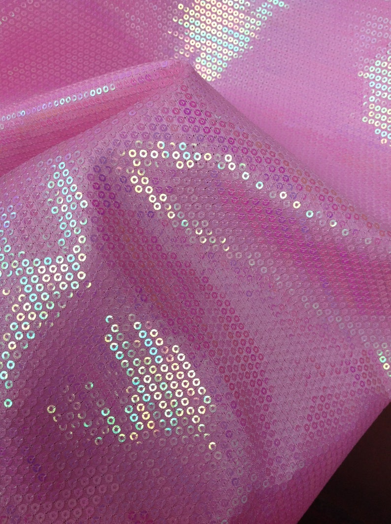 Op de afbeelding: Roze stof met iriserende pailletten in een geometrisch patroon.