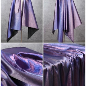 May include: A close-up of iridescent purple fabric with a subtle shimmer. The fabric is draped and folded to show its texture and sheen.