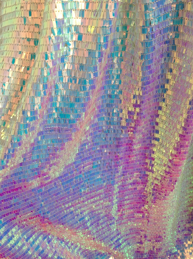 Może przedstawiać: Zbliżenie na materiał o tęczowym połysku z mieniącym się, holograficznym wykończeniem. Materiał wykonany jest z małych, kwadratowych cekin&oacute;w, kt&oacute;re tworzą fakturowany, mieniący się efekt.