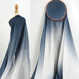 May include: A gradient fabric in shades of blue and white. The fabric is sheer and lightweight, with a soft, flowing drape. It is perfect for creating garments, scarves, or home decor.