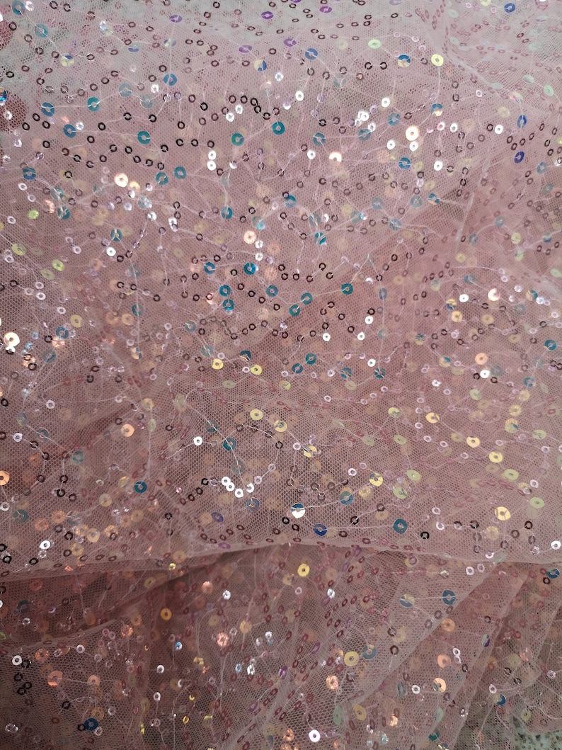 May include: Pink sheer fabric with iridescent sequins. The sequins are scattered randomly across the fabric.