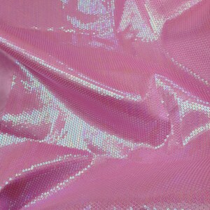 Op de afbeelding: Roze, iriserende stof met een paillettenpatroon. De pailletten zijn klein en dicht bij elkaar geplaatst, waardoor een glinsterend effect ontstaat.