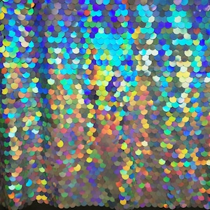 May include: A close-up of iridescent fabric with a scale-like pattern. The fabric is made of sequins in various shades of blue, green, purple, and gold.