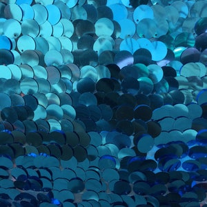 Puede incluir: Paillettes azul turquesa sobre una tela de malla. Las lentejuelas est&aacute;n dispuestas en un patr&oacute;n degradado, con lentejuelas m&aacute;s grandes en la parte superior y lentejuelas m&aacute;s peque&ntilde;as en la parte inferior.