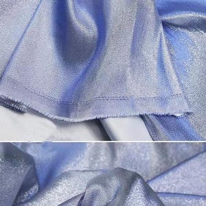 May include: A close-up of a light blue iridescent fabric with a subtle shimmer. The fabric is smooth and silky, with a slight texture.
