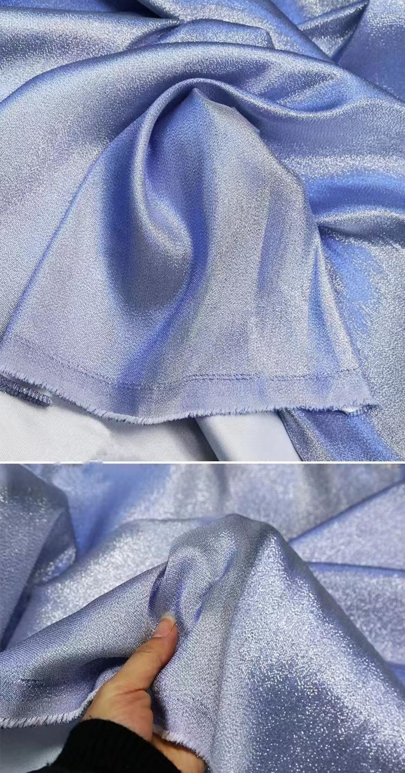 May include: A close-up of a light blue iridescent fabric with a subtle shimmer. The fabric is smooth and silky, with a slight texture.