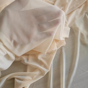 May include: A sheer, lightweight fabric in a pale beige color. The fabric is soft and drapes nicely.