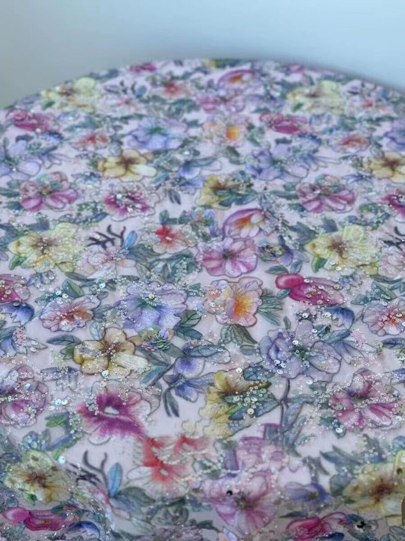 May include: A pink fabric with a floral pattern and sequins. The fabric is a sheer, lightweight material with a delicate floral design. The sequins are scattered throughout the fabric, adding a touch of sparkle.