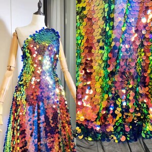Könnte beinhalten: Ein Kleid aus schimmernden Pailletten in Blautönen, Grün, Orange und Rosa. Die Pailletten sind in einem schuppigen Muster angeordnet.