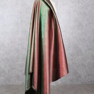 May include: A green and red iridescent fabric with a subtle shimmer. The fabric is draped over a dress form.