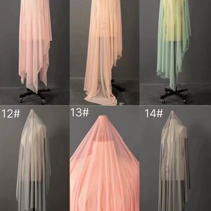 May include: Six different colors of sheer fabric draped over a dress form. The fabric is a lightweight, gauzy material that is perfect for making curtains, scarves, or other lightweight garments. The colors are peach, light pink, light green, gray, and a darker shade of pink.