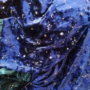 Op de afbeelding: Blauw fluweel met een sterrenbeeldpatroon van gouden sterren en een halve maan.