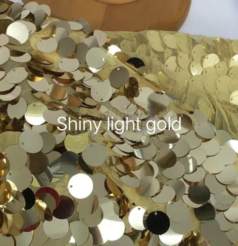 Puede incluir: Tela brillante de color oro claro con lentejuelas redondas. Las lentejuelas est&aacute;n cosidas sobre una tela de malla transparente.