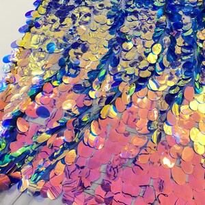 May include: Iridescent blue, gold, and pink oval sequins on a mesh fabric. The sequins are arranged in a graduated pattern, with the blue sequins at the top and the pink sequins at the bottom.