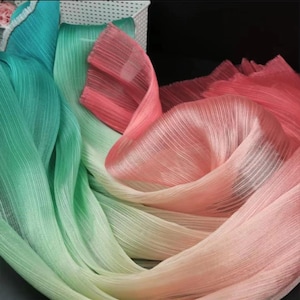 May include: A gradient ombre fabric in shades of teal, green, yellow, and pink. The fabric is sheer and has a crinkled texture.