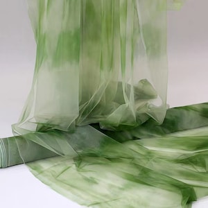 Può includere: Tessuto trasparente verde e bianco con tintura a nodo. Il tessuto è morbido e fluido, con una texture delicata.