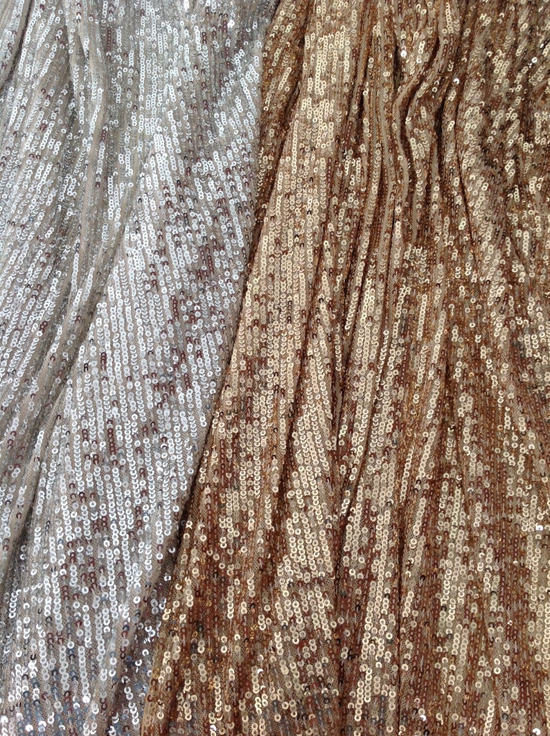 May include: Close-up of a fabric with two different colours of sequins. The left side is a light silver colour and the right side is a bronze colour.