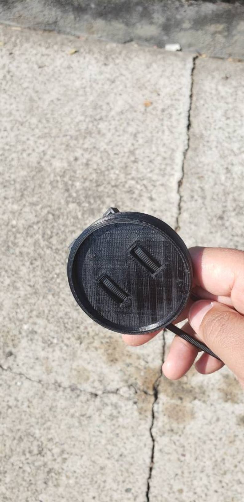 May include: Black plastic camera lens cap with two small rectangular openings.