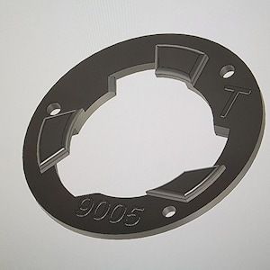 May include: A black metal ring with three cutouts and the number "9005" printed on the side. The ring has a small hole on the top and the letter "T" printed on the side.