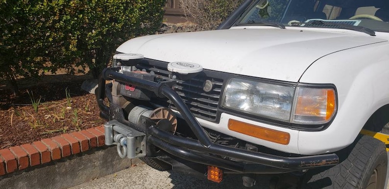 May include: White SUV with a black front bumper and a winch. The vehicle has two white antennas on the roof.