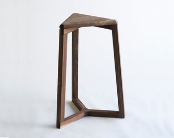 May include: A modern, triangular wooden side table. The table features a dark brown finish and a unique three-legged design. The top is a solid triangle shape, and the legs are angled for stability. A stylish accent piece for any room.