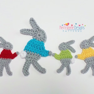 May include: Four crocheted gray bunny rabbits wearing colorful sweaters. The bunnies are standing in a row, facing forward. The sweaters are blue, green, yellow, and red.