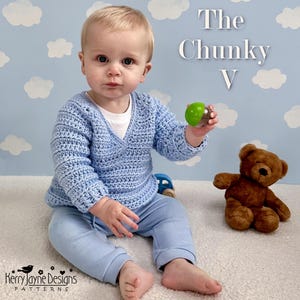 May include: A baby wearing a light blue crochet wrap sweater and matching pants. The baby is holding a green and clear rattle. A brown teddy bear and a small blue car are also in the image. Text on the image reads "The Chunky V".