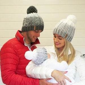 Może przedstawiać: Trójka osób w dopasowanych szarych i białych czapkach z pomponami w stylu ombre. Czapki mają brązową skórzaną metkę z tekstem "Henry Jane Designs PATTERNS".