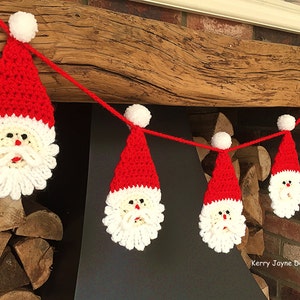May include: A red and white crocheted Santa Claus garland with pom-poms hanging from a wooden beam. The garland is made of yarn and features a white beard and a red hat.