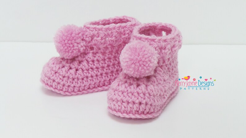 Puede incluir: Un par de botines de beb&eacute; de ganchillo rosa con pompones en la parte superior.